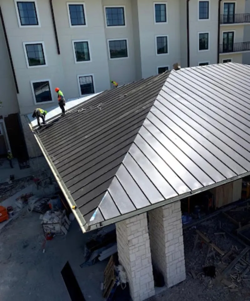 Crew installing standing seam metal roof panels on a commercial project in Rosemount